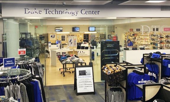 A view of Duke Technology Center in Duke Stores includes racks of clothing in the foreground, with computers in the background