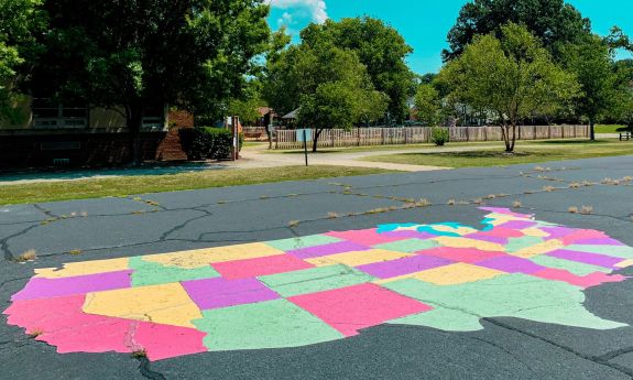 A map of the United States is drawn in chalk on pavement
