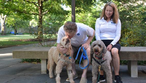 Duke University President Vincent E. Price plants a kiss on the forehead of his dog, Scout, while his wife, Annette, and labradoodle, Cricket, take a break during a walk around West Campus in July 2022. Photo by Stephen Schramm.
