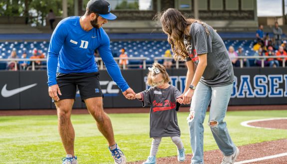 duke baseball player helps young girl run the bases at Coombs Stadium