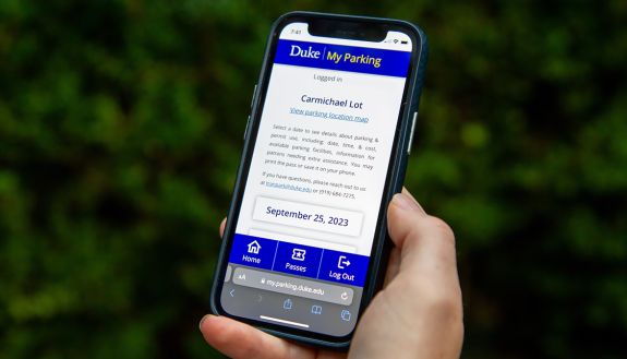 A person holds an iPhone with MyParking on the screen.