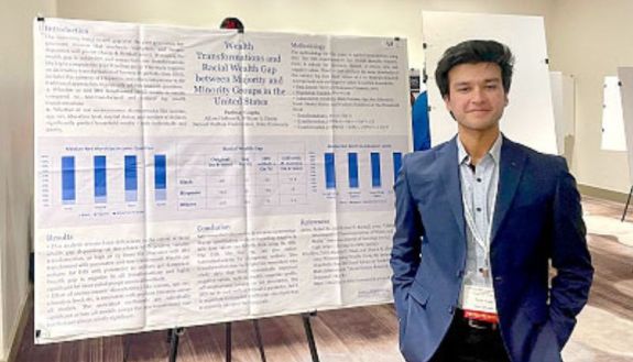 Parinay Gupta standing next to poster for a conference