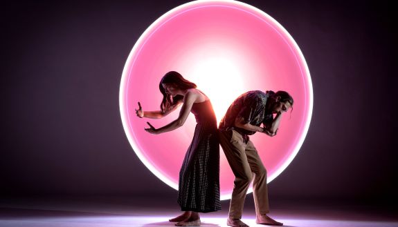 Two dancers in front of a pink circle