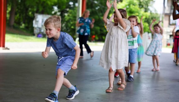 Duke Children's Campus students as they walk into their graduation celebration clapping to music.