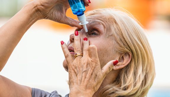 woman putting eye drops in her eye