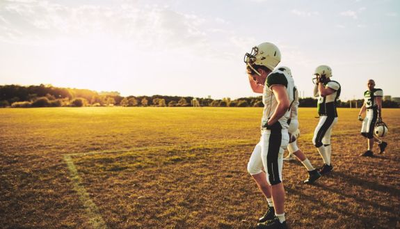 high school football students walk off field after a hot practice