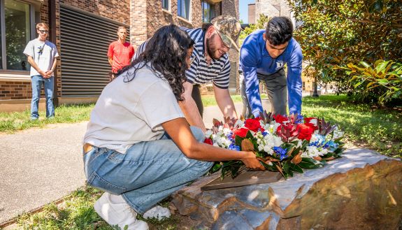 ﻿Juniors Ranjan Jindal, VP of Keohane Quad, Tara Singh, President of Keohane Quad, and Austin Brown, Communications Coordinator for Keohane Quad lay a wreath at Duke’s 9/11 Memorial plaque near the grove of six trees planted behind Keohane Quad