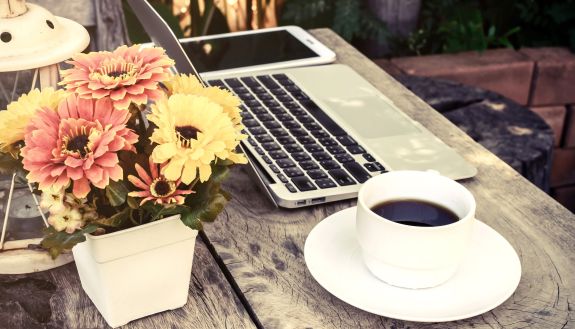 A cup of coffee on a table next to a laptop