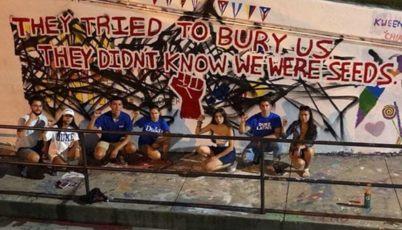 Latino students in front of the East Campus Bridge. Writing: "They Tried to bury us. They didn't know we were seeds"