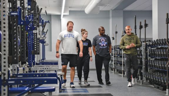 Four people in a weight room