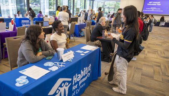 Student at the volunteer fair talking to people at a Habitat for humanities table