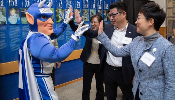 Duke's Blue Devil mascot high-fives representatives from Duke Kunshan University in China