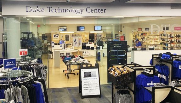 A view of Duke Technology Center in Duke Stores includes racks of clothing in the foreground, with computers in the background