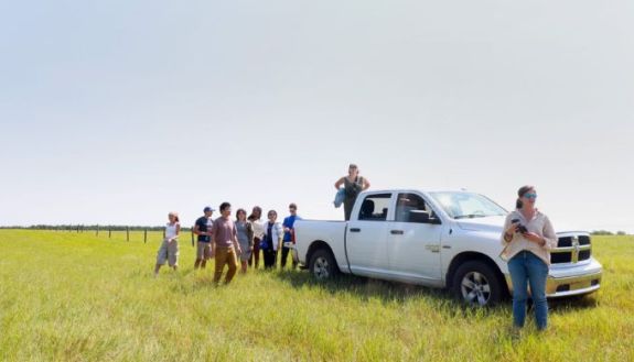 students standing in a field with a white truck