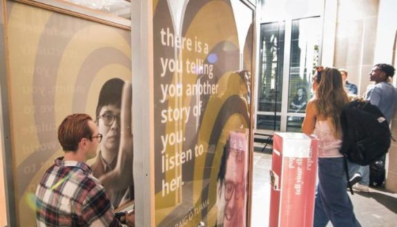 Students in a booth with people walking by