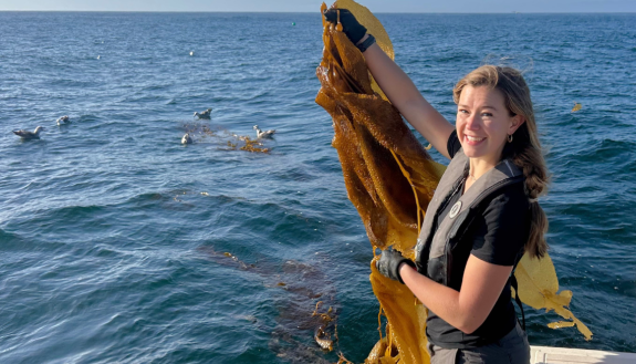 Eliza Harrison holding seaweed on a boat