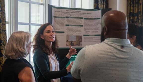 Person standing in front of a presentation board talking to others.