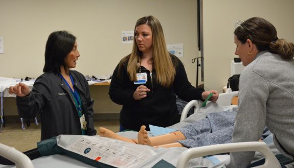 Three people around a hospital bed.