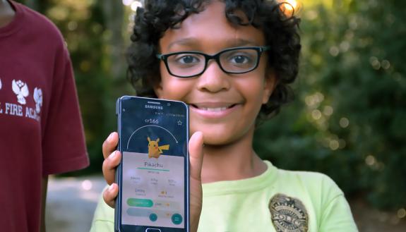 Rubin Polk shows off a newly caught Pikachu he found during a Pokemon GO walk organized by LIVE FOR LIFE, Duke's employee wellness program. Rubin attended with his sister, Nisha, and mom, Sharlini Sankaran, a Duke employee. Photo by Bryan Roth.