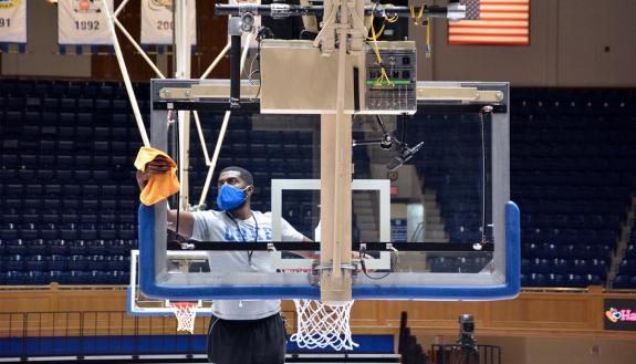 Associate Director of Athletics Facilities and Projects Jamal White wipes down the backboard prior to the Duke Women's Basketball team's showdown with South Carolina. Photo by Stephen Schramm.