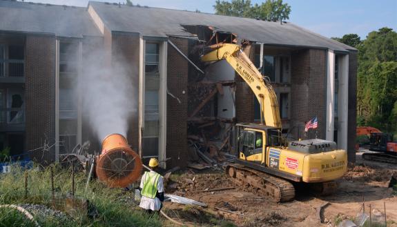Water sprays onto a former Central Campus apartment to reduce dust during building removal. Crews began demolishing buildings on Central Campus during the morning of Aug. 13. Photo by Jonathan Black.
