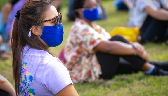 Students wearing masks and talking at a physical distance from each other.