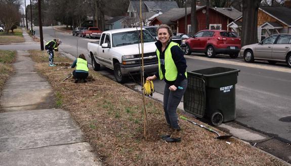 Duke Hospital nurse Ali Homan smiles as she plants trees in Durham's Walltown neighborhood.