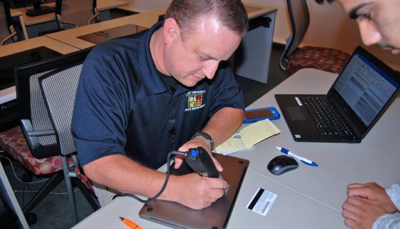 Duke Police Community Services Officer Kelly George engraves a student's laptop.