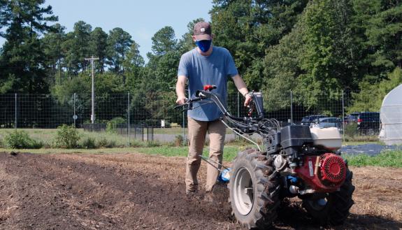 Graduate student Garrett Corwin tills the soil at Duke Campus Farm. Photo by Stephen Schramm.