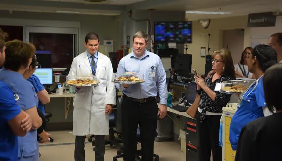 Neurosurgeons John Barr, left, and Steven Cook, right, hand out baked goods and thank you cards to employees at Duke Regional Hospital's Emergency Department. Photos by Jonathan Black.