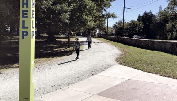 A blue emergency phone shown amid a campus scene.