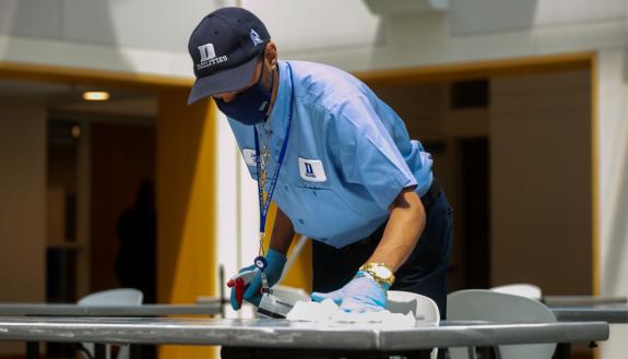 James White, a housekeeper, sweeps floors and sanitizes high touch surfaces such as table tops and chairs at the Fuqua School of Business.