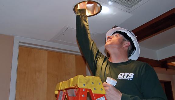 Installer Ryan Roberson puts LED lights into fixtures in Sanford Hall.