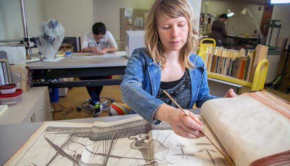 Conservator for Special Collections Erin Hammeke cleans pages of an 18th-century encyclopedia in the Verne and Tanya Roberts Conservation Laboratory in Perkins Library.