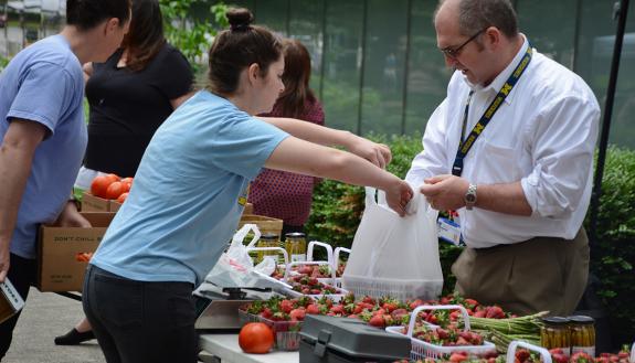 Eric Lipp, far right, buys strawberries from the Lyon Farms stand at the Duke Farmers Market. Photos by Jonathan Black.