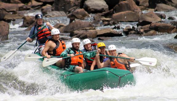 Michael Barnes, at left, helps guide a raft full of friends through rapids during a recent trip.