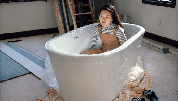 artist Cici Cheng in a bathtub. “This photograph is filled with many different emotions. When I see this photograph, I see my past and present, parts of myself that are in conflict with each other, my memories and parts of my identity.”