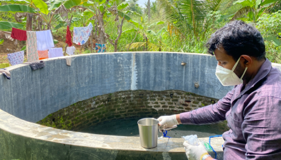 Sandeep Hasinthara, a research technician based at the University of Ruhuna, collects a water sample from a CKDu impacted well in Bālayāwewa, Sri Lanka.