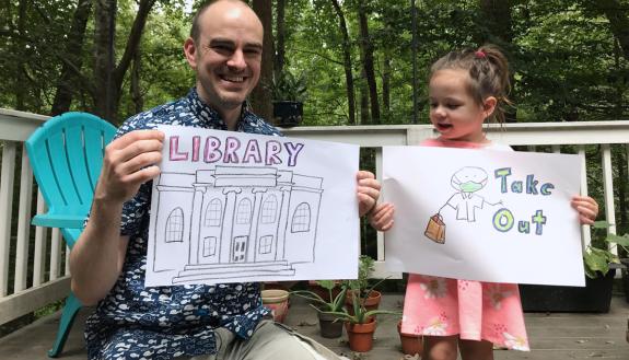 Jamie Keesecker and his daughter Naima hold up drawings used in the Library Takeout video. Photo courtesy of Jamie Keesecker.