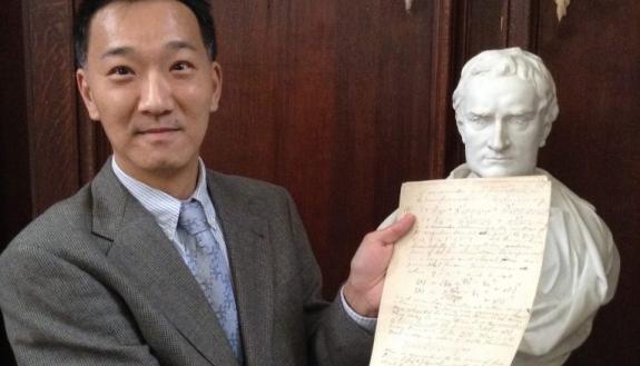 Professor Ken Ono of Emory University poses with a bust of Newton and one of Ramanujan’s legendary notebook pages. Source: IFC Films.