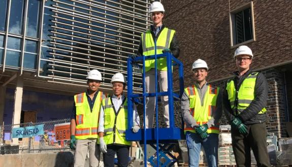 The scissor-lift safety device design team with their prototype across the street from where Skanska is constructing Duke's newest engineering building.