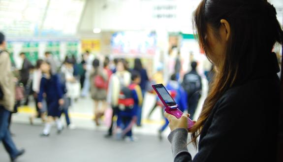 Girl consults her cell phone screen in a crowded subway station