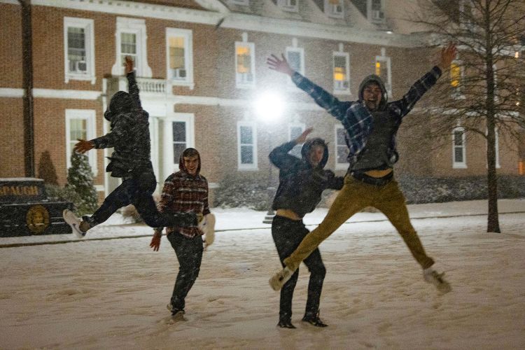 Students jump into the air while playing in the snow on East Campus.