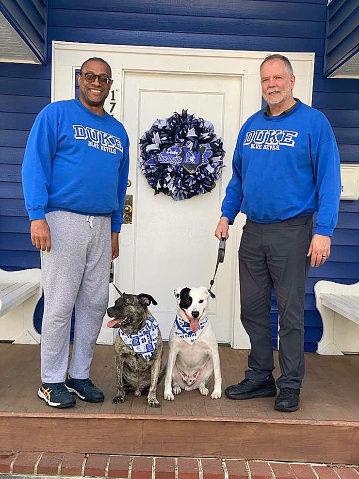 On Duke game days, Maxie Hipps-Figgs, left, and Mark Hipps-Figgs, right, wear their lucky Duke sweatshirts. They also make sure their dogs, Buddy and Lucky, have on their lucky bandanas. Photo courtesy of Maxie and Mark Hipps-Figgs.