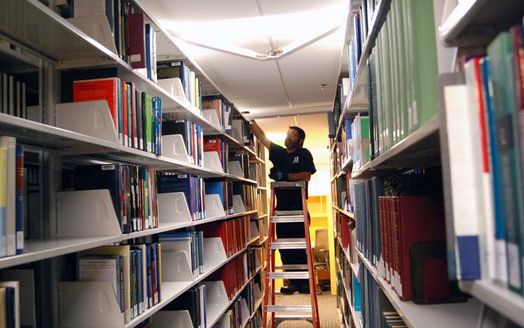 General Maintenance Mechanic Chip Meade fixes a light at Goodson Law Library. Photo by Stephen Schramm.