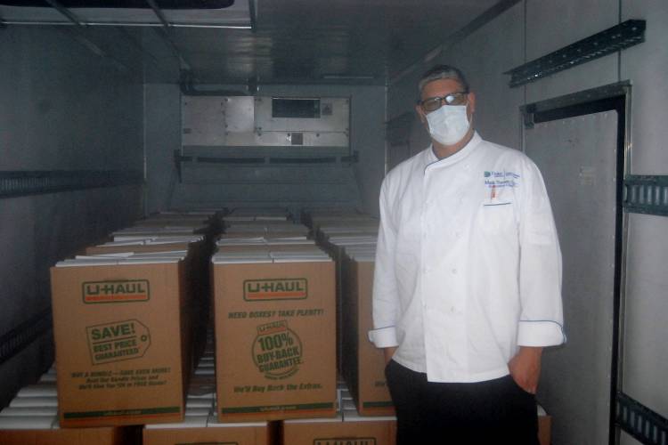 Mark Turner stands in front of 2,000 boxed lunches on a cooled truck.