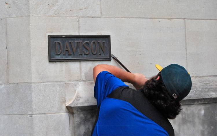 A crew worked to remove the existing plaque at the Davison Building before replacing it with a new Duke blue plaque with white lettering.