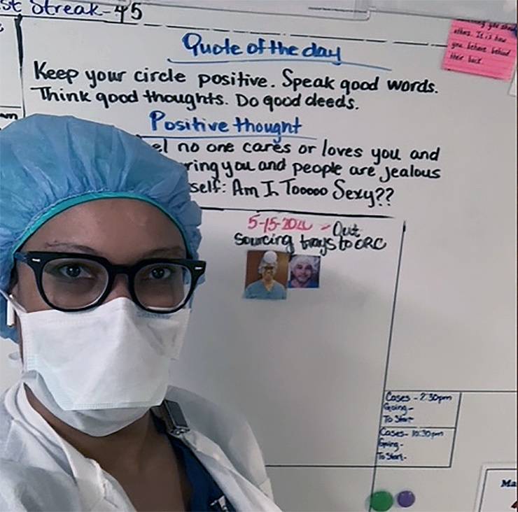 Taneshia Walker poses in front of the whiteboard where employees write quotes and positive thoughts each day. Photo courtesy of Taneisha Walker.