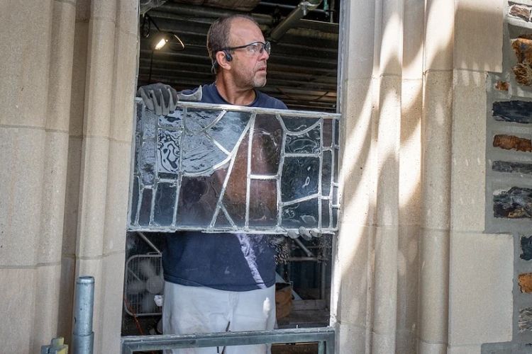 Andrew Goldkuhle works on removing a lower panel of the “Esther” stained glass assemble from its tracery in Duke Chapel’s Narthex.