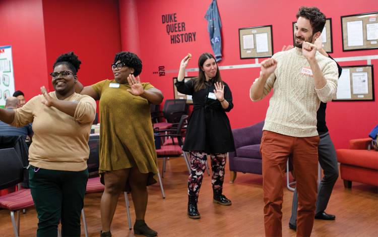 Nicholas Antonicci, far right, director of Duke’s Center for Sexual & Gender Diversity, dances with friends and colleagues from WorkOUT, the LGBTQ staff and faculty group, during a holiday potluck. Photo by Justin Cook.